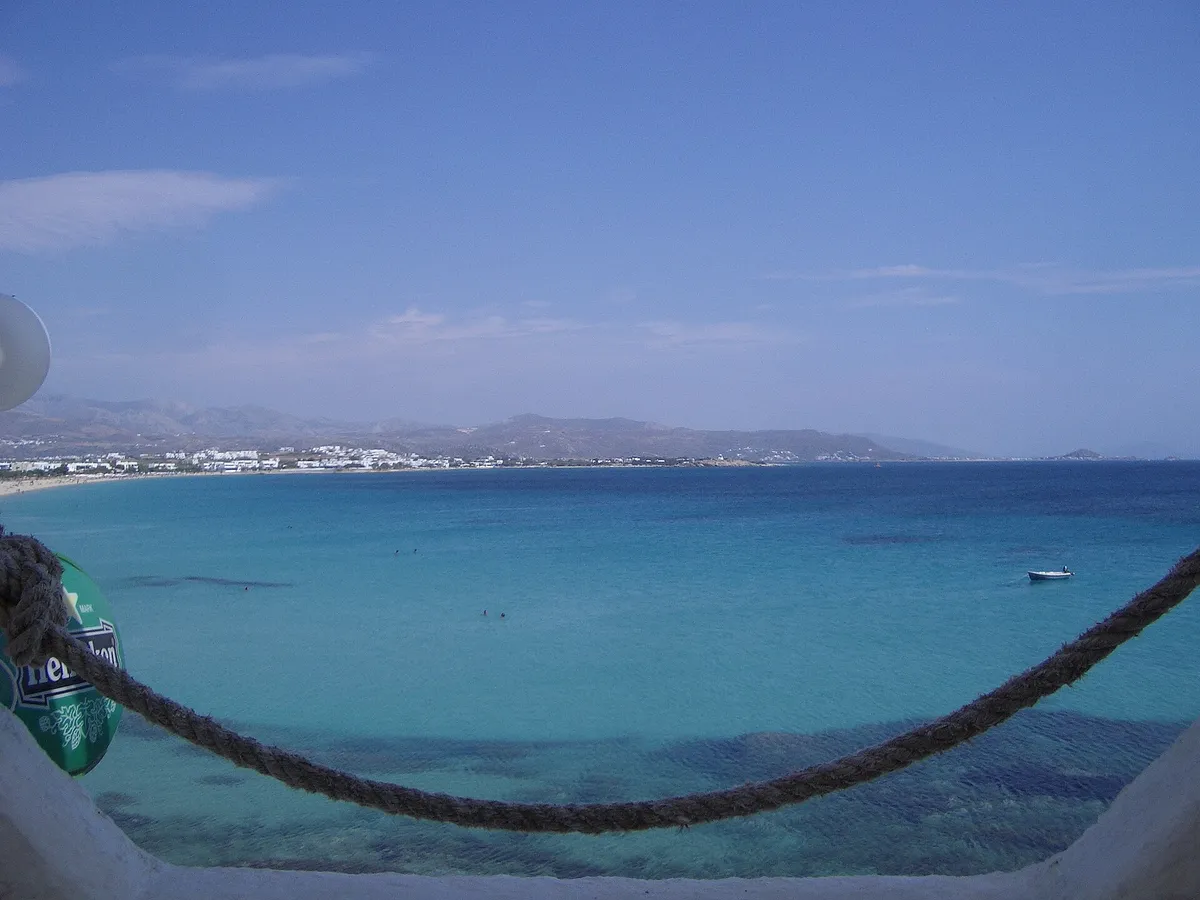 Turquoise bay on the west coast of Naxos seen from a beach terrace with a small boat at anchor