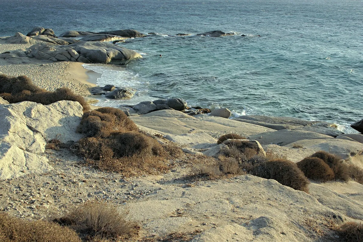 Granite rocks and autumn shoreline with calm sea at Agia Anna, Naxos, in soft October light